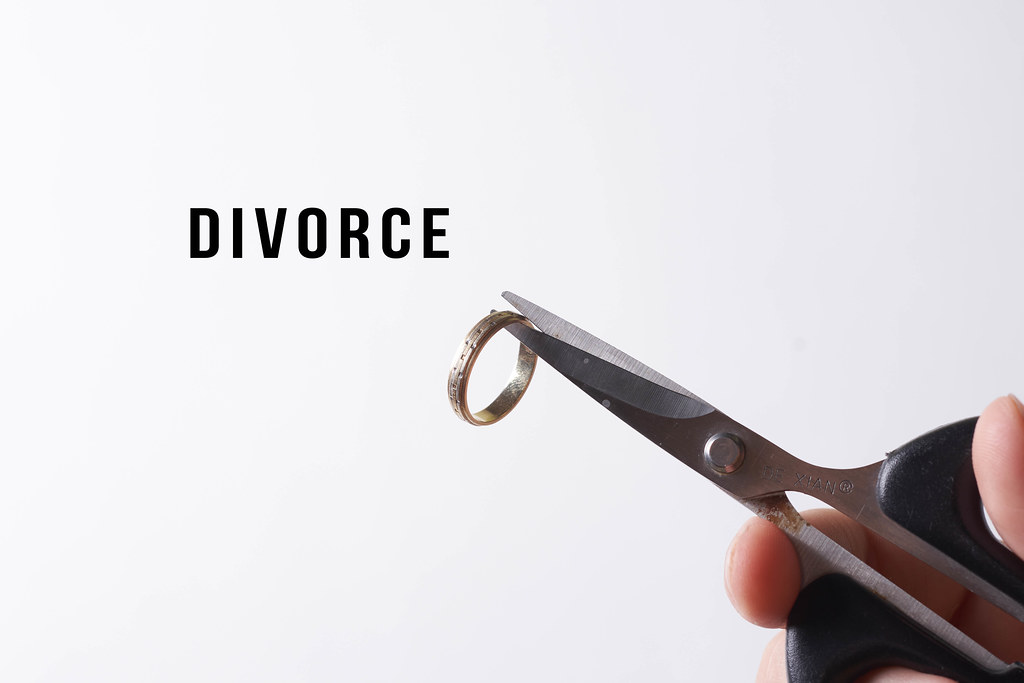 Divorce concept - person hand cutting wedding ring with scissors