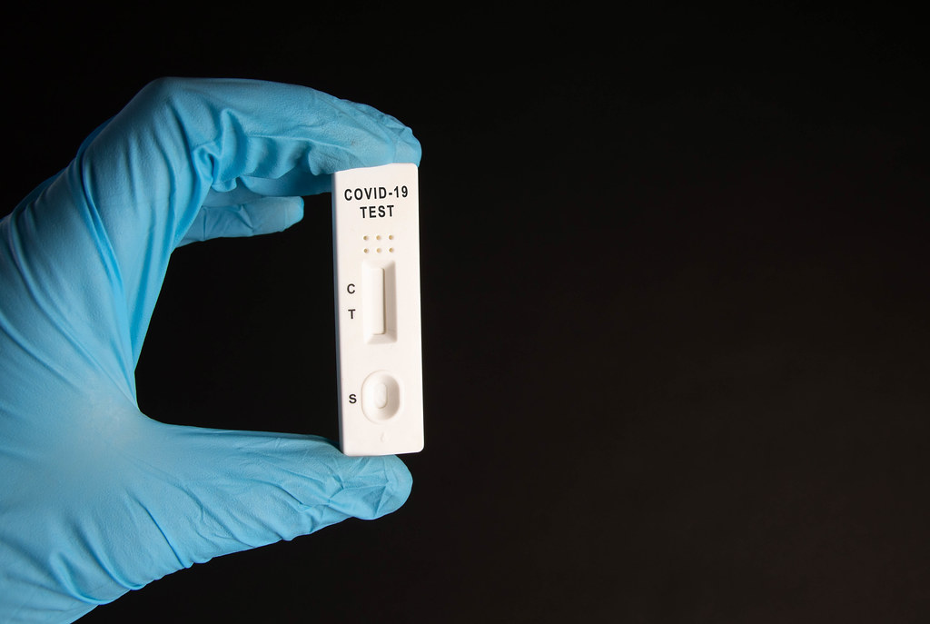 Doctor holding a test kit for viral disease tests with the COVID-19 on black background