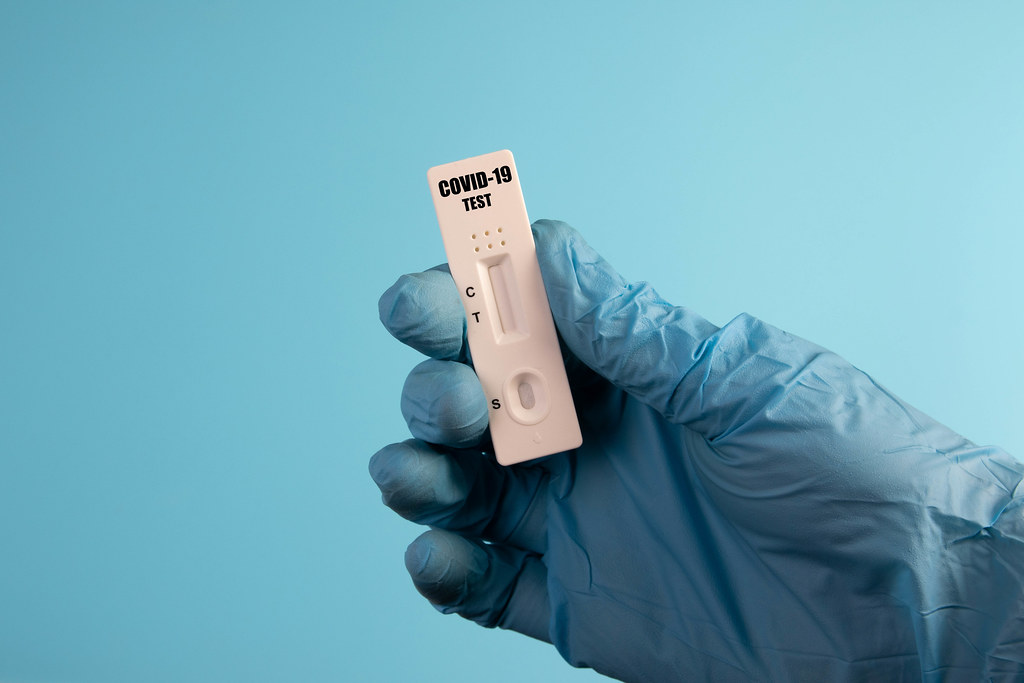 Doctor holding a test kit for viral disease tests with the COVID-19 on blue background