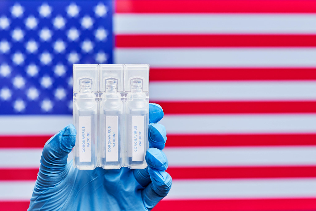 Doctor holds three doses of Covid-19 vaccines against American flag