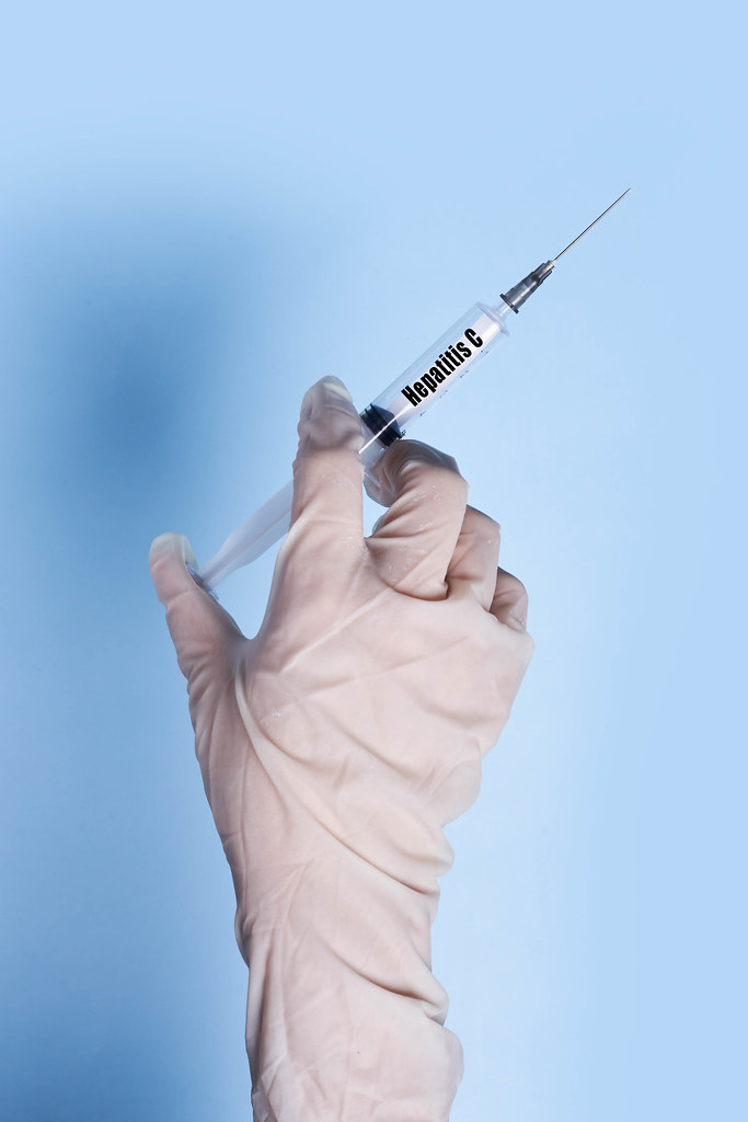 Doctor in medical gloves holds a syringe with Hepatitis C text on it