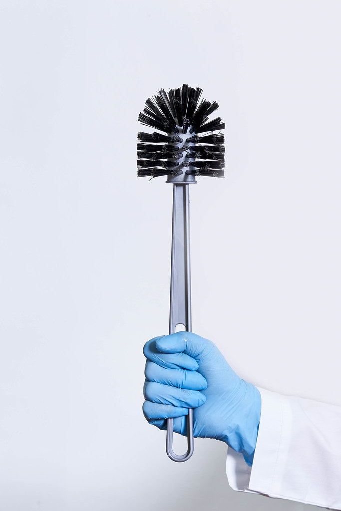 Doctor in medical gloves holds a toilet brush