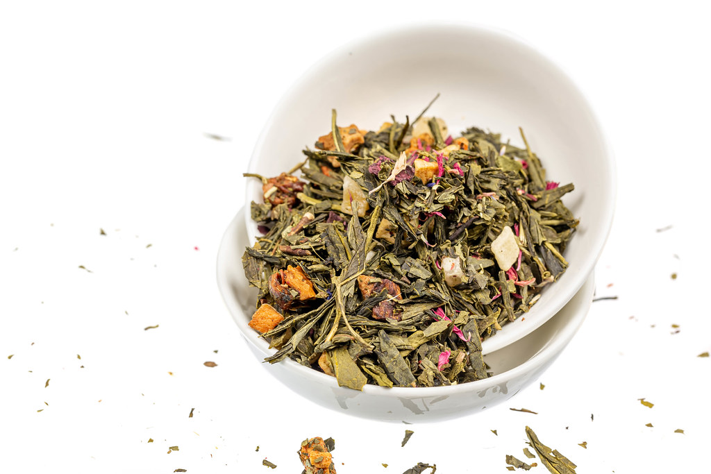 Dried green tea leaves with citrus slices, dried fruits and petals