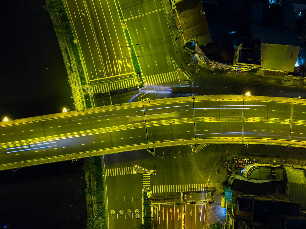 Drohnen Nachtfoto von einer Brücke in der Draufsicht mit Lichtstreifen von Fahrzeugen in Ho Chi Minh Stadt, Vietnam