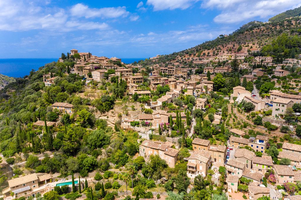 Drone photo of the charming village of Deià on a hill by the sea in the Serra de Tramuntana on Majorca