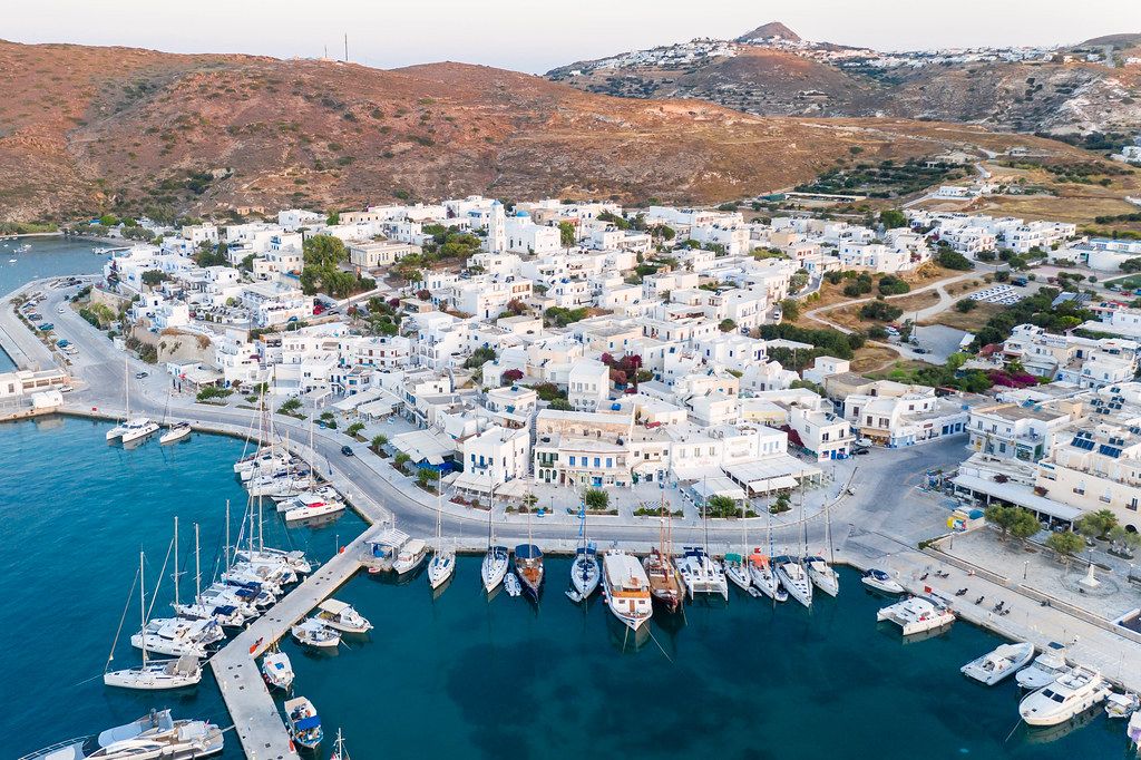 Drone pic: pier with sailboats and yachts, turquoise sea and typical white-blue houses in Adámas, Milos