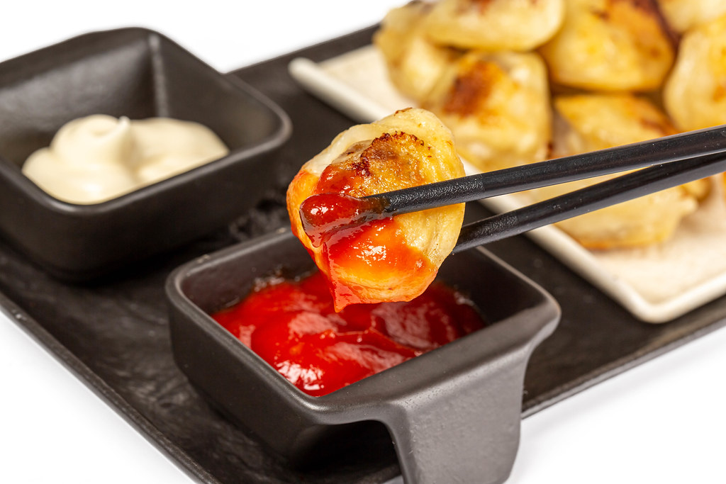 Dumplings with tomato sauce and chopsticks, close-up