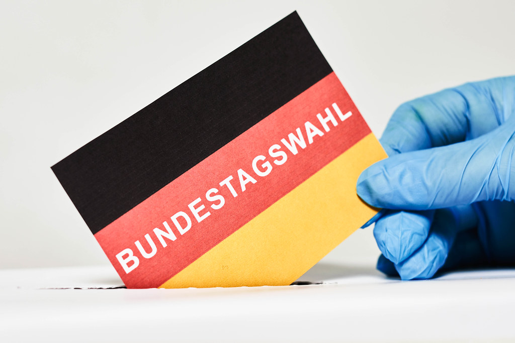 Ein Mann im medizinischen Handschuh, der bei den Bundestagswahlen abstimmt