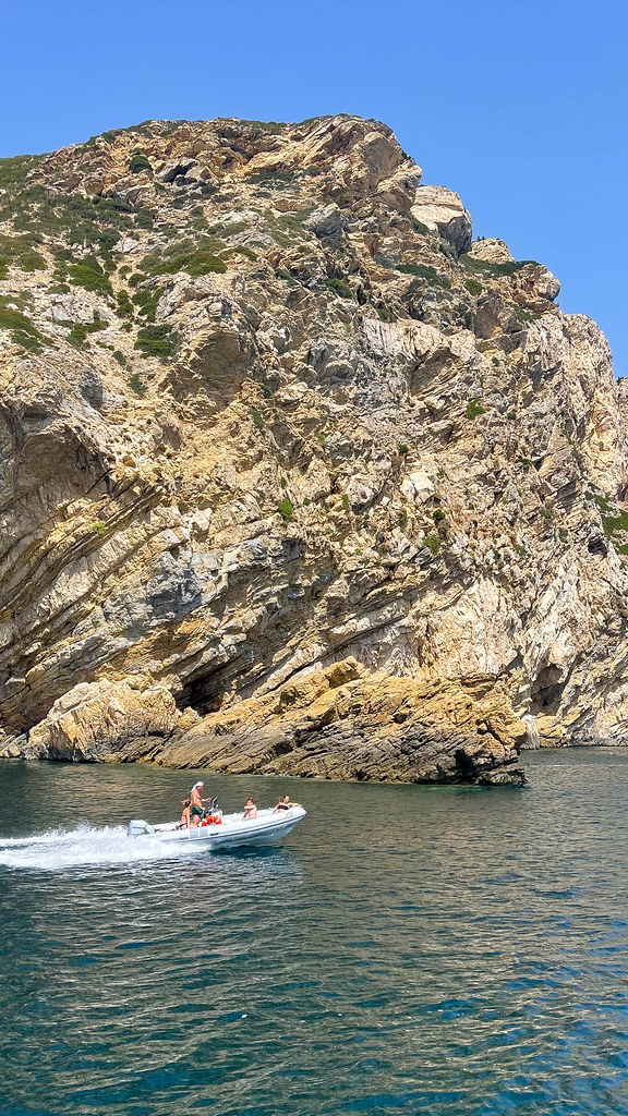 Ein Motorboot fährt an der felsigen Küste der kaum bewohnten Insel Kyra Panagia bei Alonnisos entlang