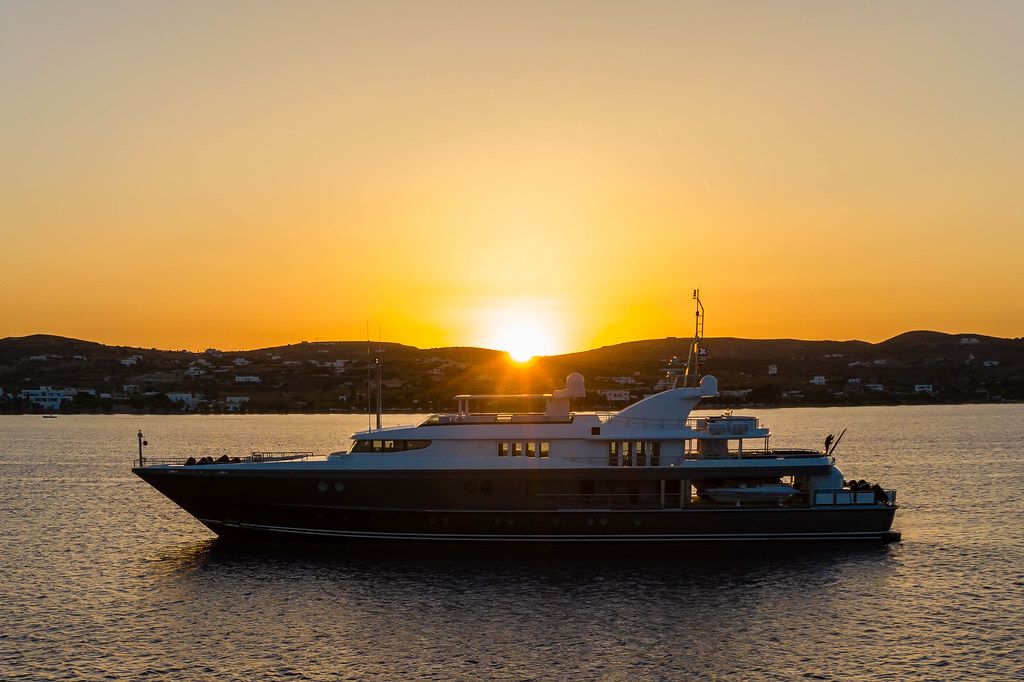 Eine Yacht und der Sonnenuntergang am Hafen von Adámas, Milos, Griechenland