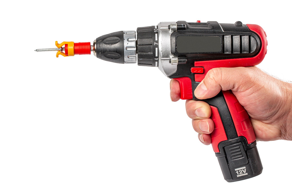 Electric screwdriver with screw holder in man hand