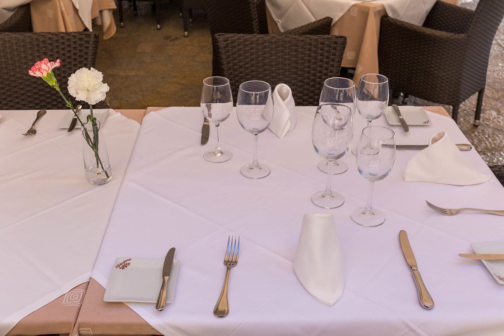 Elegant restaurant dinner table with folded white napkins, flowers, wine and water glasses and cutlery