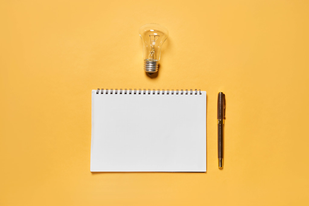 Empty notepad with pen and a bulb - concept of writing creative ideas