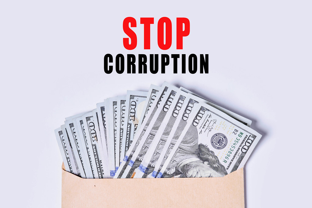 Envelope filled with us dollar banknotes and STOP CORRUPTION text