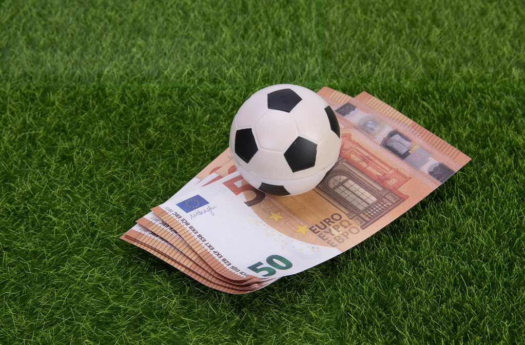 Euro banknotes with soccer ball on grass field