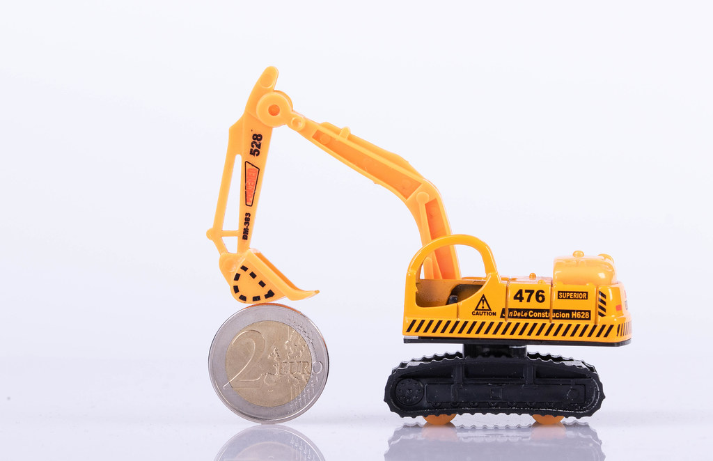 Excavator with 2 euro coin on white background