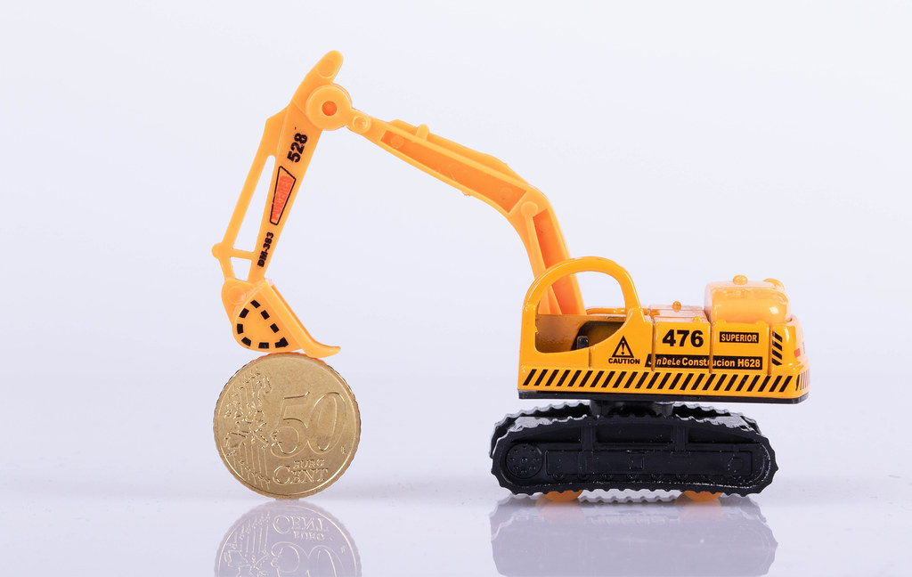 Excavator with 50 cent coin on white background