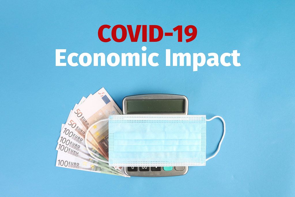 Face mask on calculator and money with Covid-19 Economic Impact text