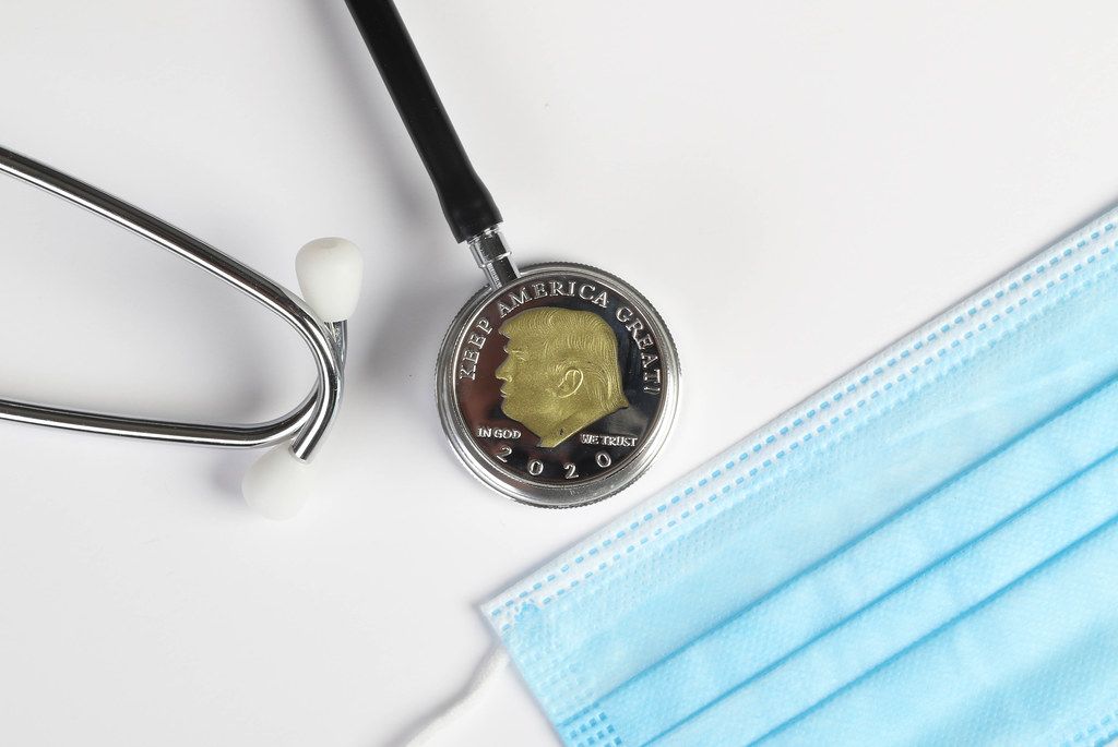 Face mask, stethoscope and silver coin with Donald Trump on white background