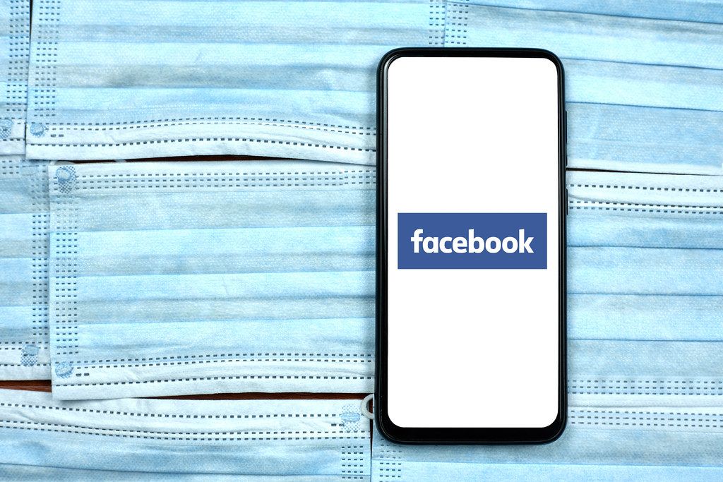 Facebook app on smartphone display. Global company during coronavirus crisis