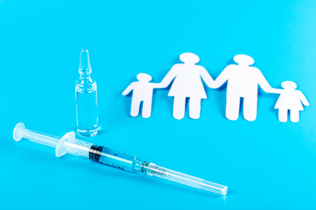 Family immunization concept, ampoule, syringe with vaccine and family silhouette on blue background