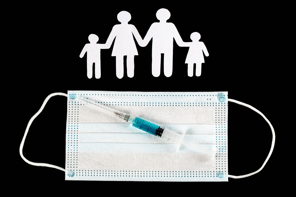 Family vaccination concept on dark background with syringe and mask