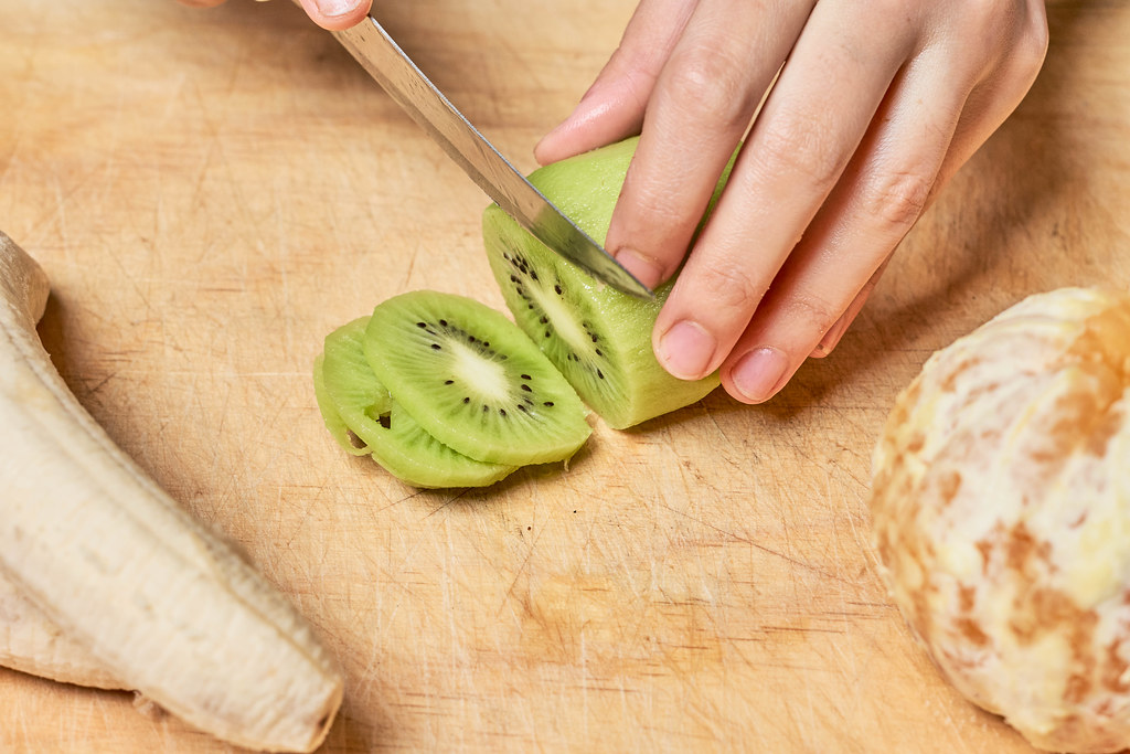 Female hands cutting kiwi fruit