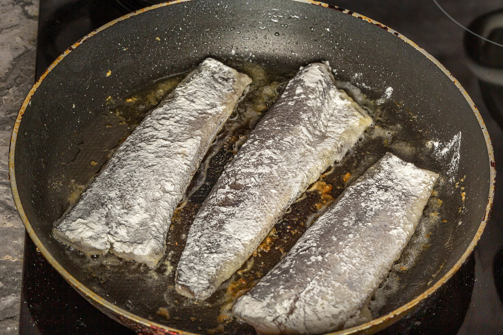 Fish fillet with flour fried in a frying pan, cooking hake