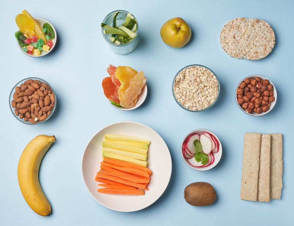 Flat lay image of fresh fruits, vegetable slices, nuts and gluten-free bread for snack