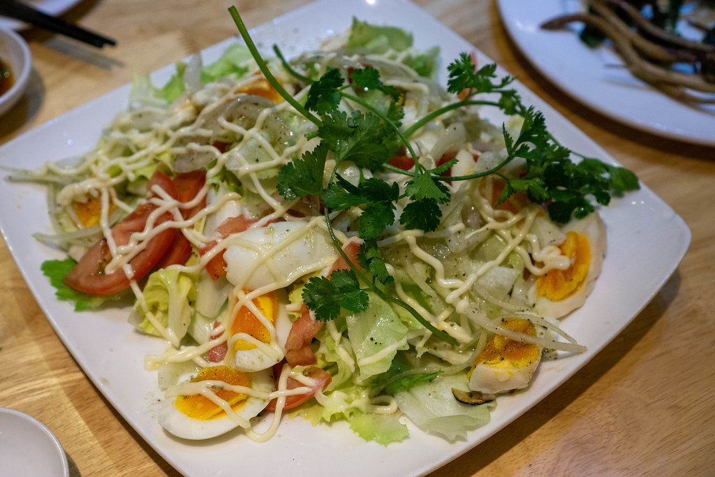 Food Photo of Mixed Salad with Boiled Eggs, Tomatoes, Onions, Parsley and Mayonnaise on a Plate in a Restaurant