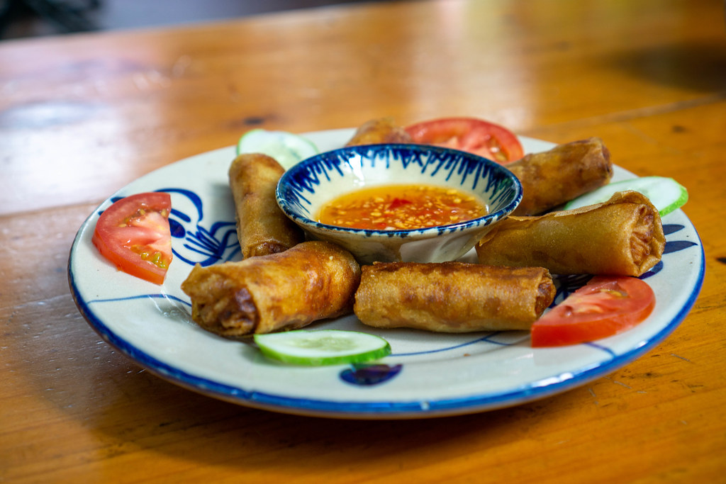 Food Photo of Vietnamese Fried Spring Rolls with Fish Sauce Dip on a Ceramic Plate in a Restaurant