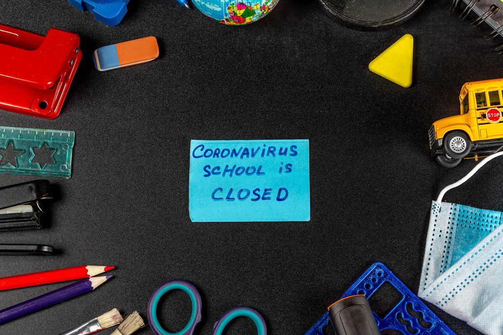 Frame of school supplies on a black background with the inscription-coronavirus school closed