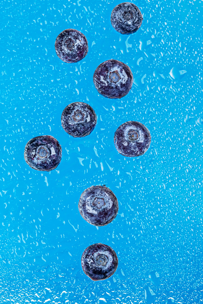 Fresh blueberries on blue background with water drops
