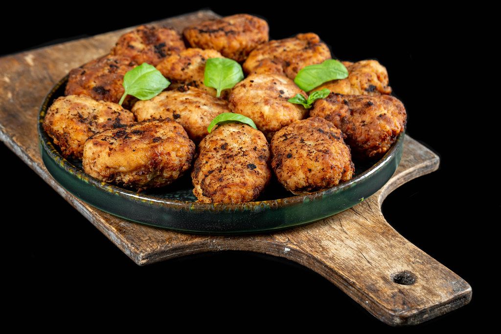 Fresh homemade fried cutlets with basil leaves on dark background