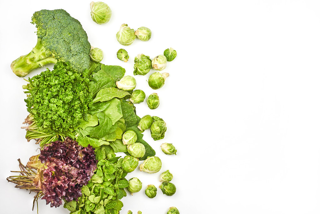 Fresh leafy greens and Brussels sprouts on white background