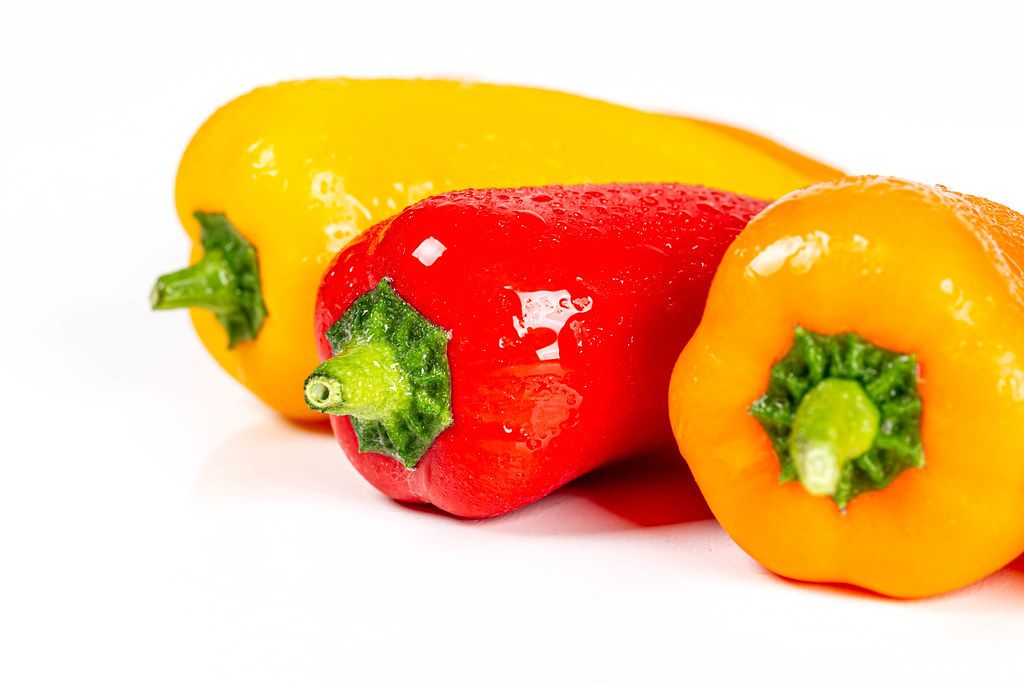 Fresh multicolored bell peppers on a white background
