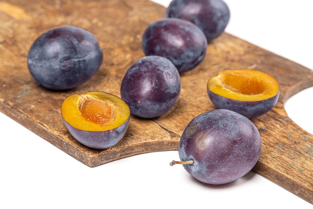 Fresh plums on old wooden kitchen board