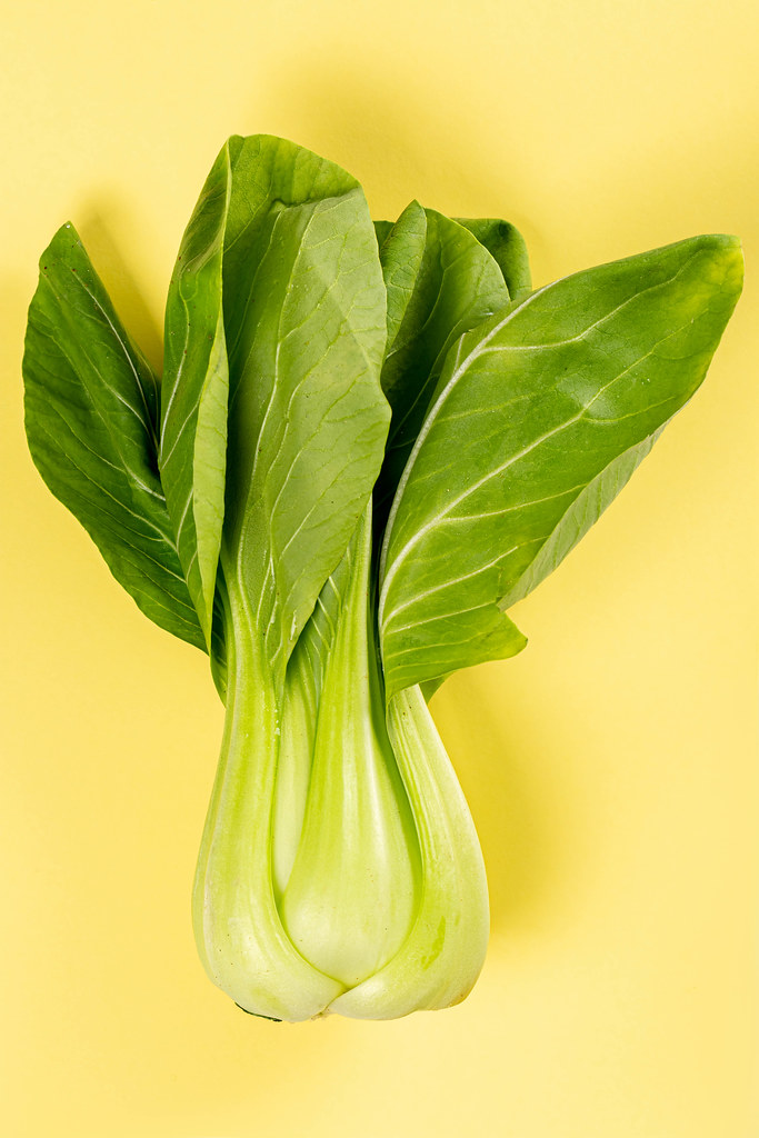 Fresh raw pak choy cabbage on yellow background