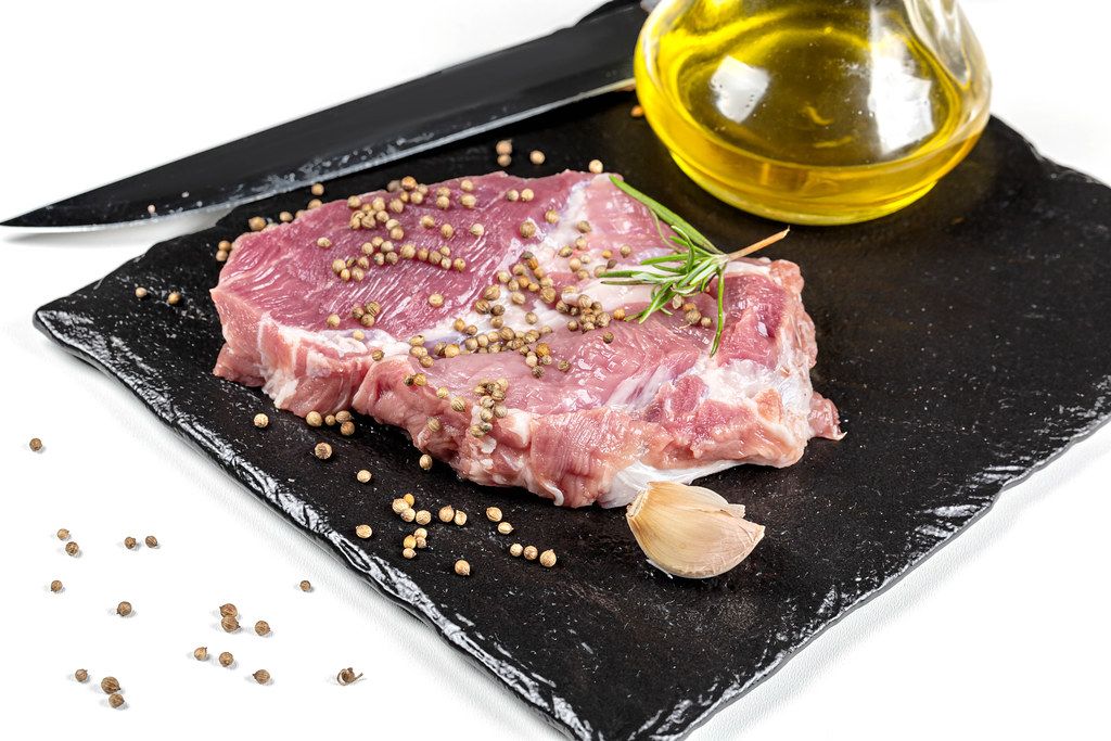 Fresh raw steak with spices, olive oil, garlic and knife