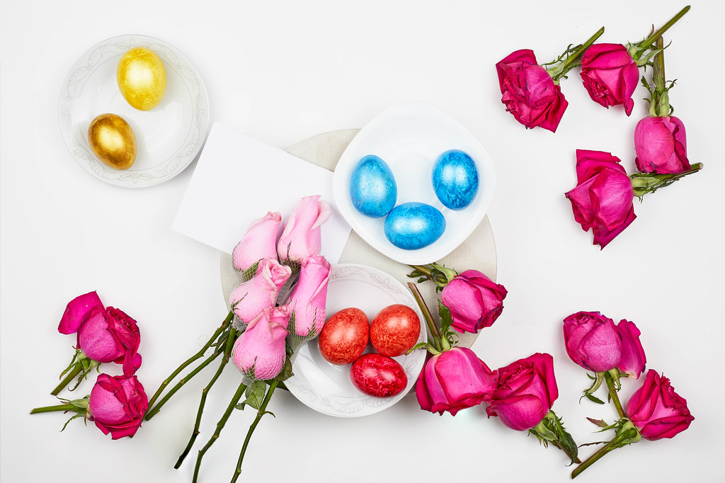 Fresh spring flowers and decorative Easter eggs on white