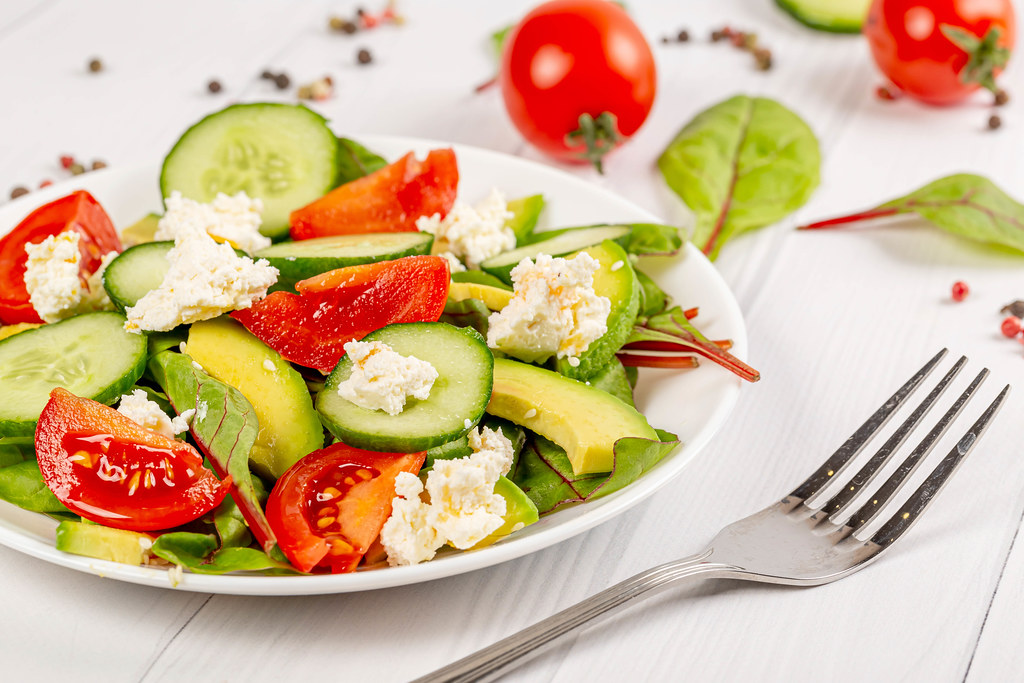 Fresh vegetable salad with tomatoes, cucumbers, avocado, cottage cheese and beet leaves