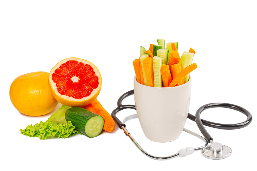 Fresh vegetables and a stethoscope on a white background, the concept of health care