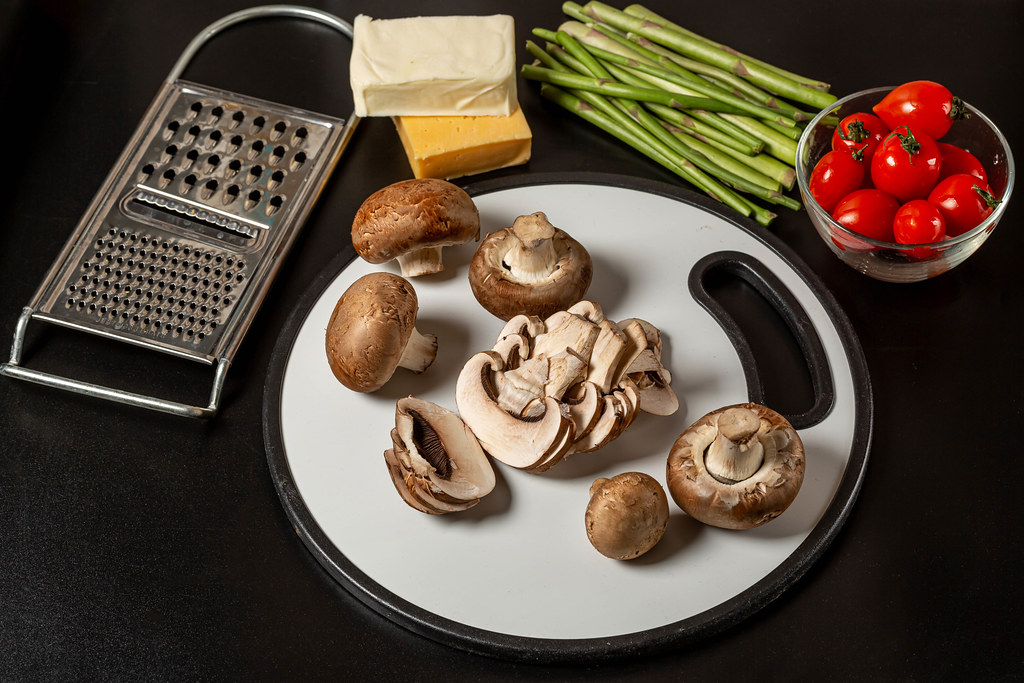 Fresh vegetables and mushrooms on a dark background with cheese and grater