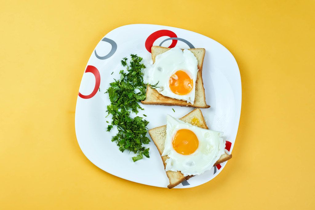 Fried egg with toast bread and parsley on white plate