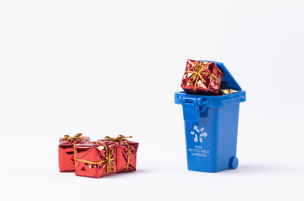Garbage bin full of gifts on white background
