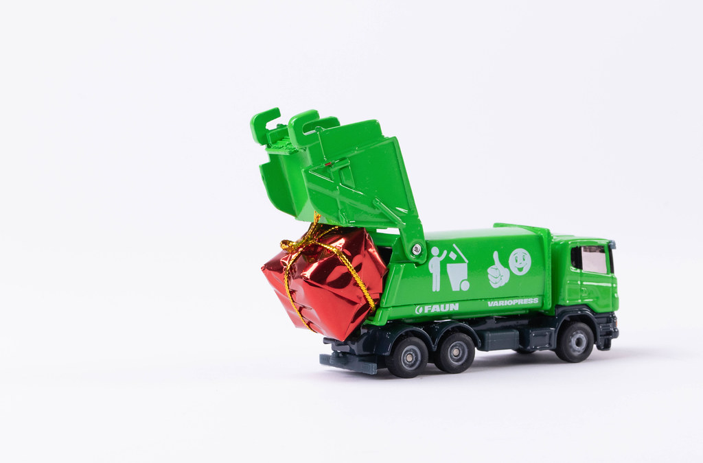 Garbage truck with gift on white background