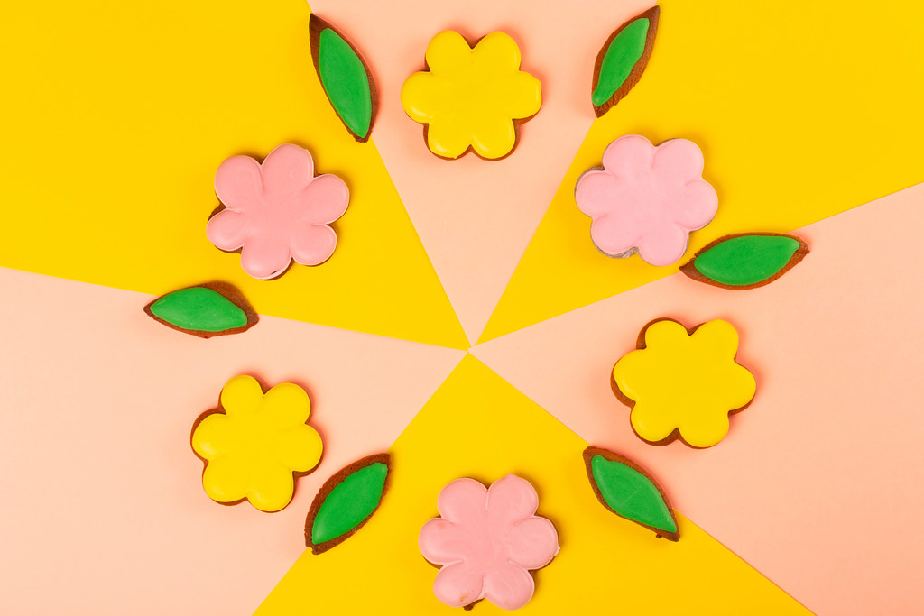 Gingerbread cookies - flowers with colored glaze on a pink and yellow background, top view