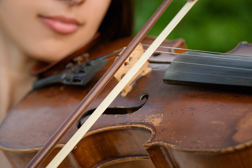 Girl playing on the old violin outdoor, close up