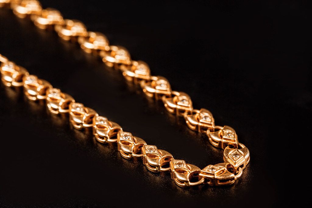 Gold bracelet with links in the form of hearts on a black, close-up