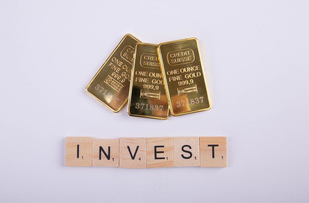 Gold bricks with Invest text on wooden blocks